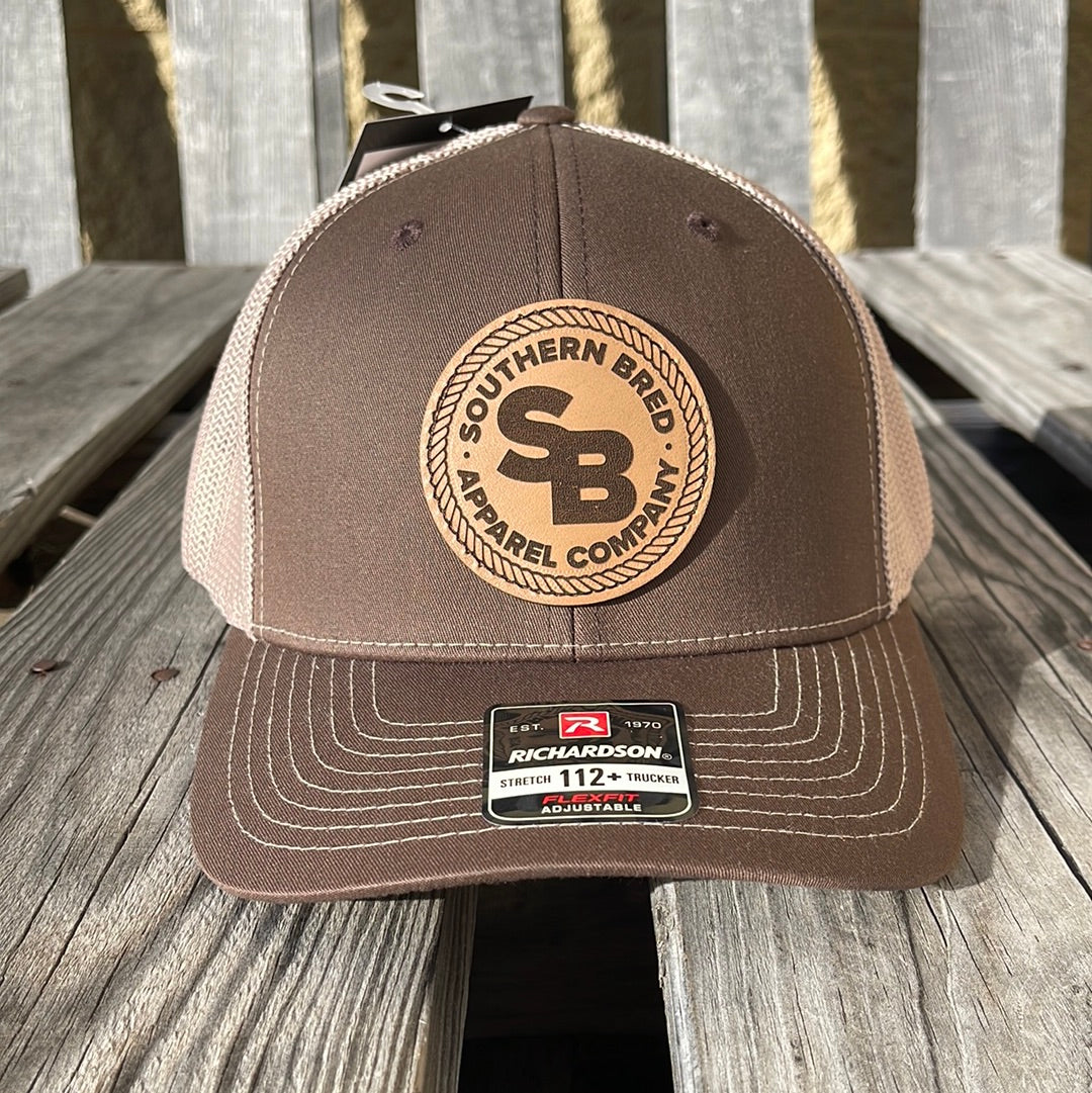 Brown cap with leather SBAC patch on a wooden surface