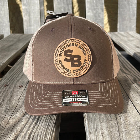 Brown cap with leather SBAC patch on a wooden surface