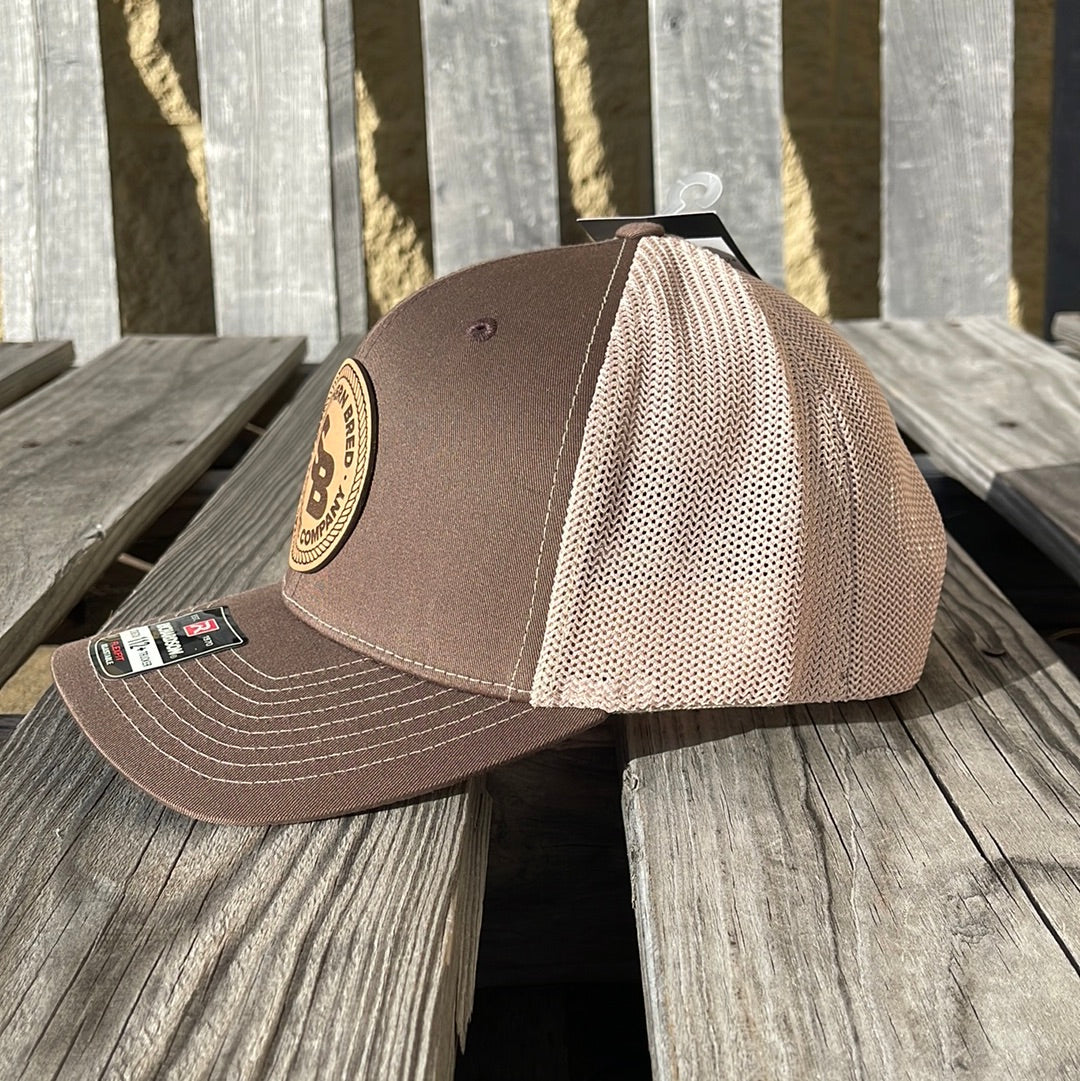 Brown and beige cap with a patch on a wooden surface