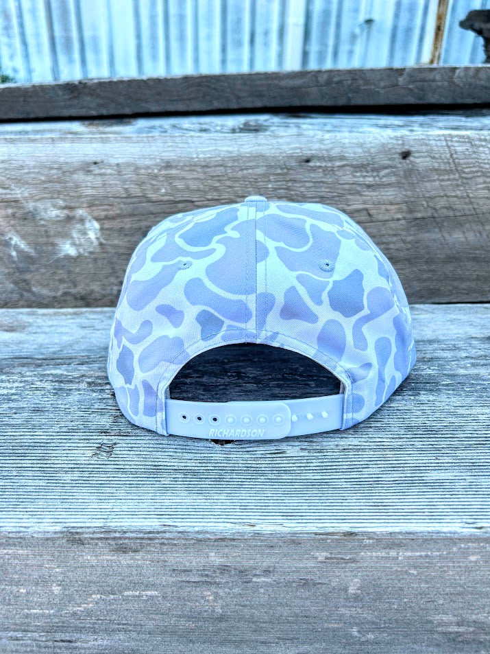 Light blue camouflage cap on a wooden surface with a metal sheet background