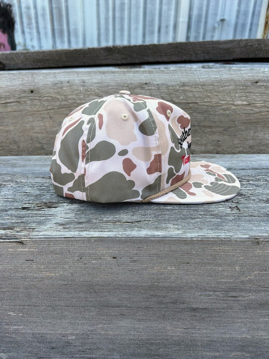 Camouflage-patterned cap on a wooden surface with a metal sheet background