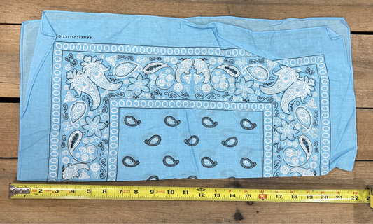 Sky Blue bandana with white paisley patterns on a wooden surface, measured by a yellow tape measure.